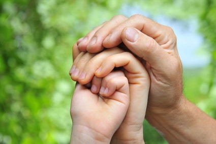 father's hand holds a palm of his wife and daughter